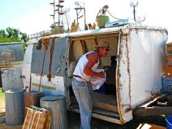 a man stands outside his rundown camper trailer